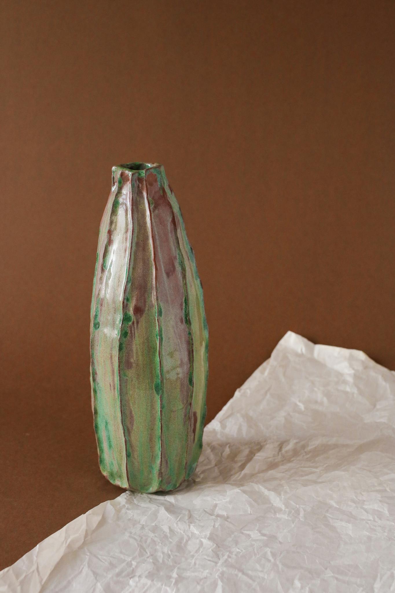 A colorful ceramic vase displayed on crumpled paper, ideal for minimalist decor