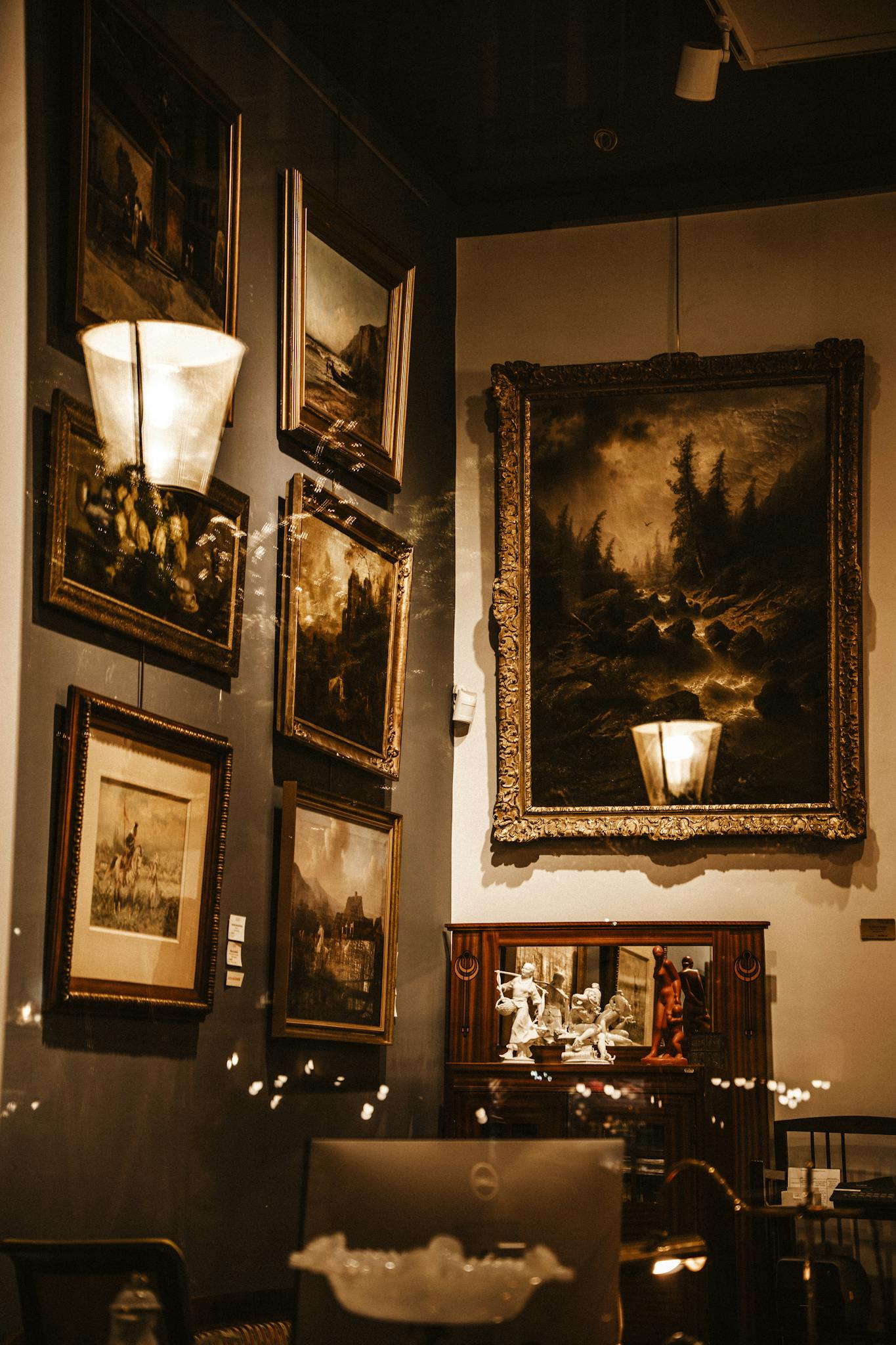 A cozy gallery corner showcasing luxury paintings and sculptures in warm lighting.