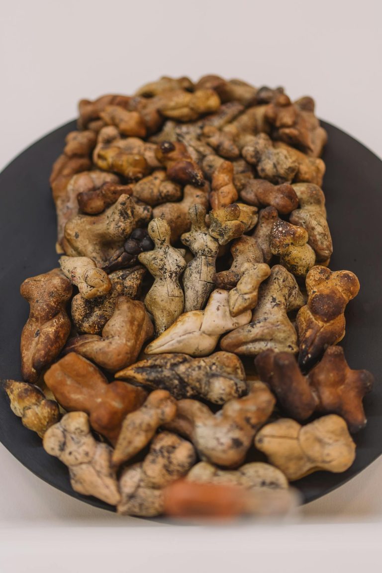 A detailed close-up of a handmade ceramic figurine collection arranged on a display table.