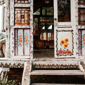 Beautifully painted rustic wooden doorway with floral designs and intricate details.