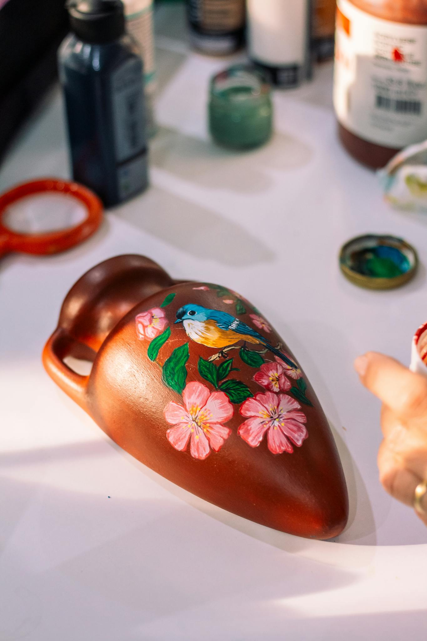 Colorful terracotta vase with bird and floral painting, perfect for decor.