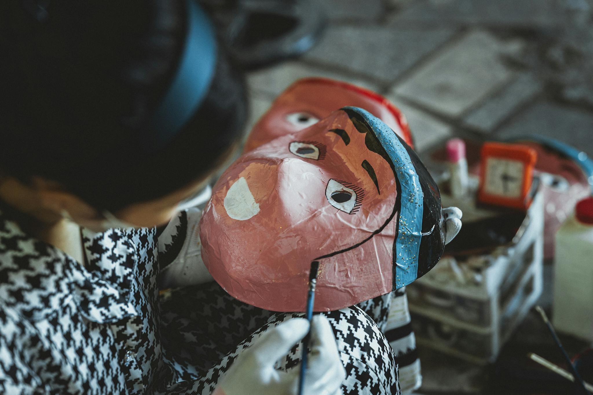 Person skillfully painting a traditional vibrant mask, showcasing craftsmanship and cultural artistry.