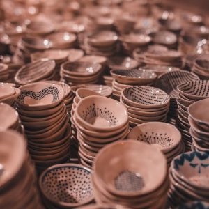 Rows of intricately designed handmade ceramic bowls stacked closely in soft lighting.